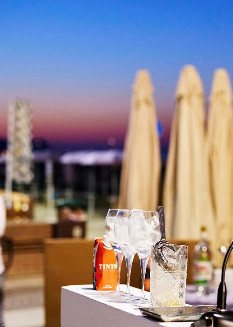 De hoek van een draagbare bar met de glazen, voor de zee bij zonsondergang