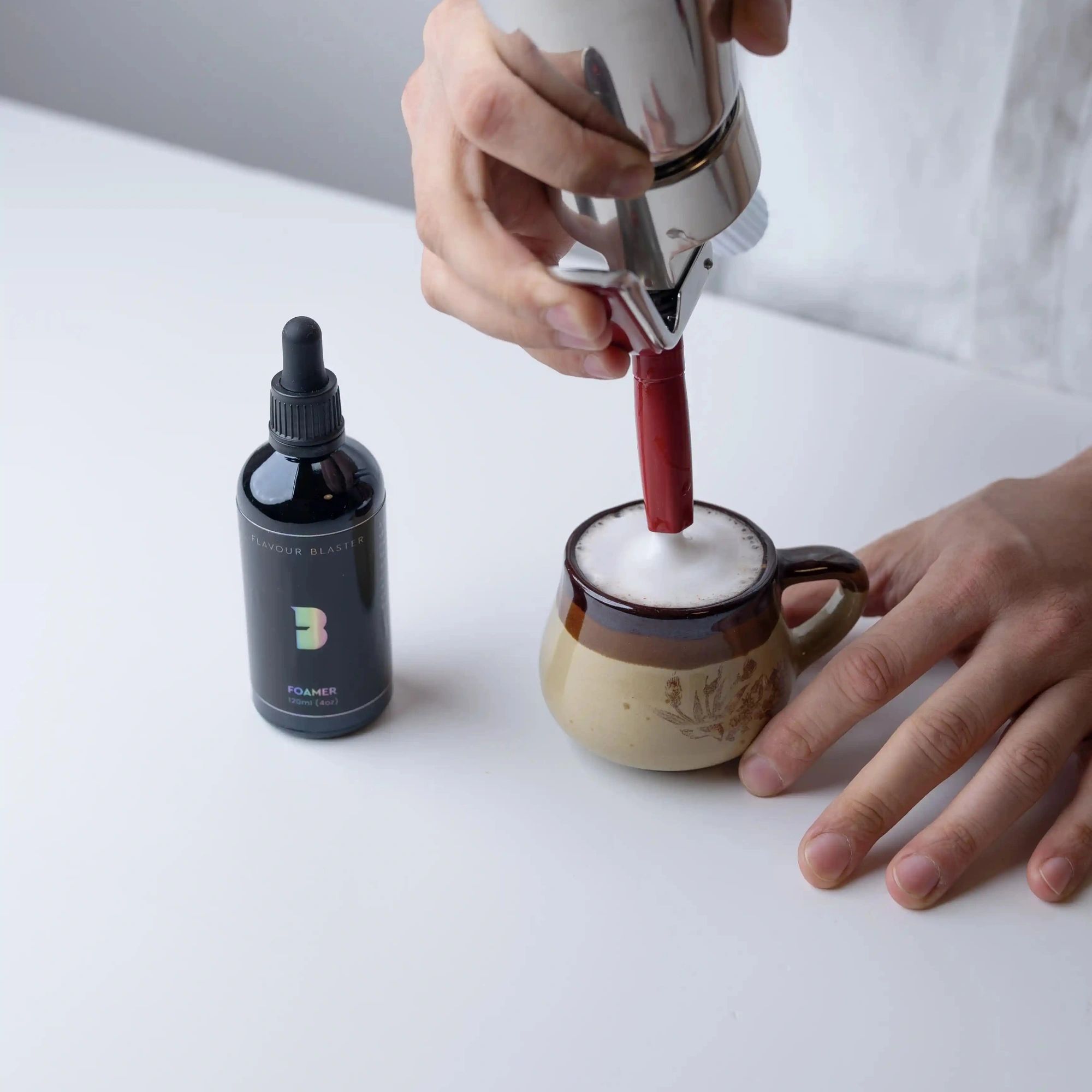 cocktail foamer Flavour Blaster: foam made with a siphon on a ceramic cup, bottle alongside